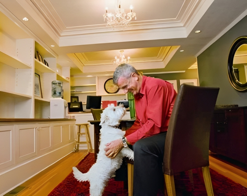 Brad Friesen leaning down to pet his West Highland White Terrier, Fergus.