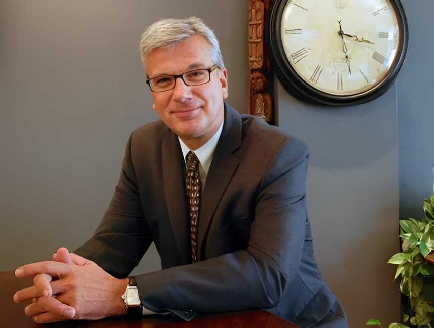 A portrait of Brad Friesen seated at a desk.